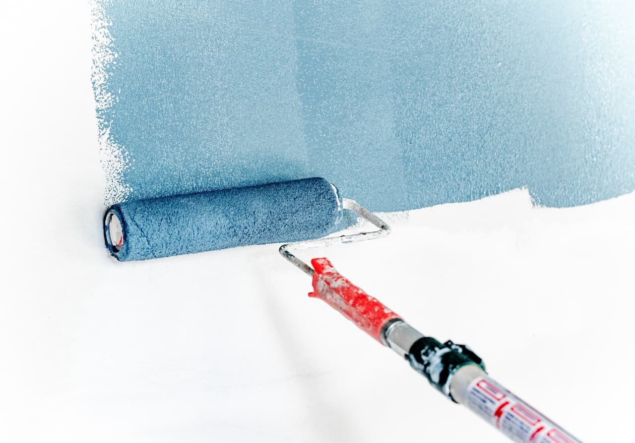 Paint roller applying fresh blue paint to an interior wall