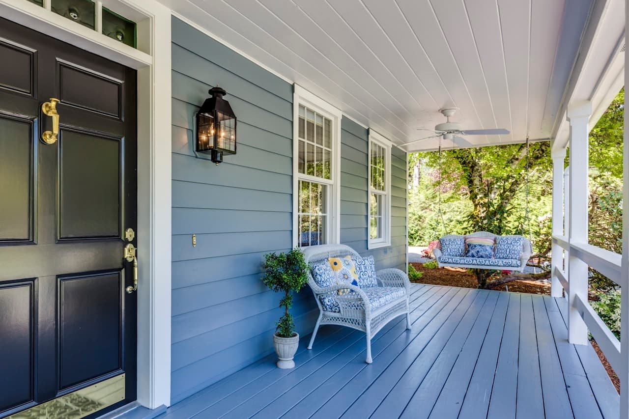 Freshly painted blue house siding with white trim and a covered porch