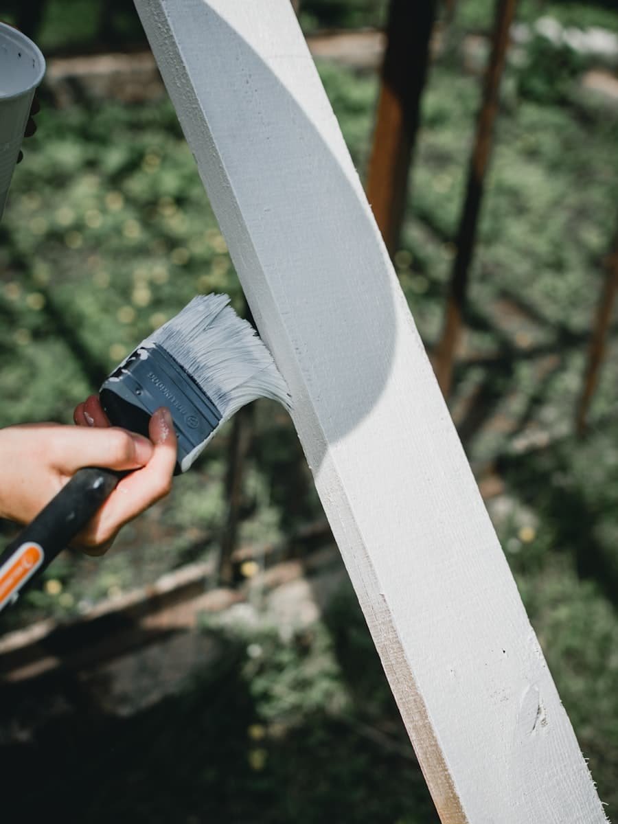 Brush applying white paint to interior wood trim