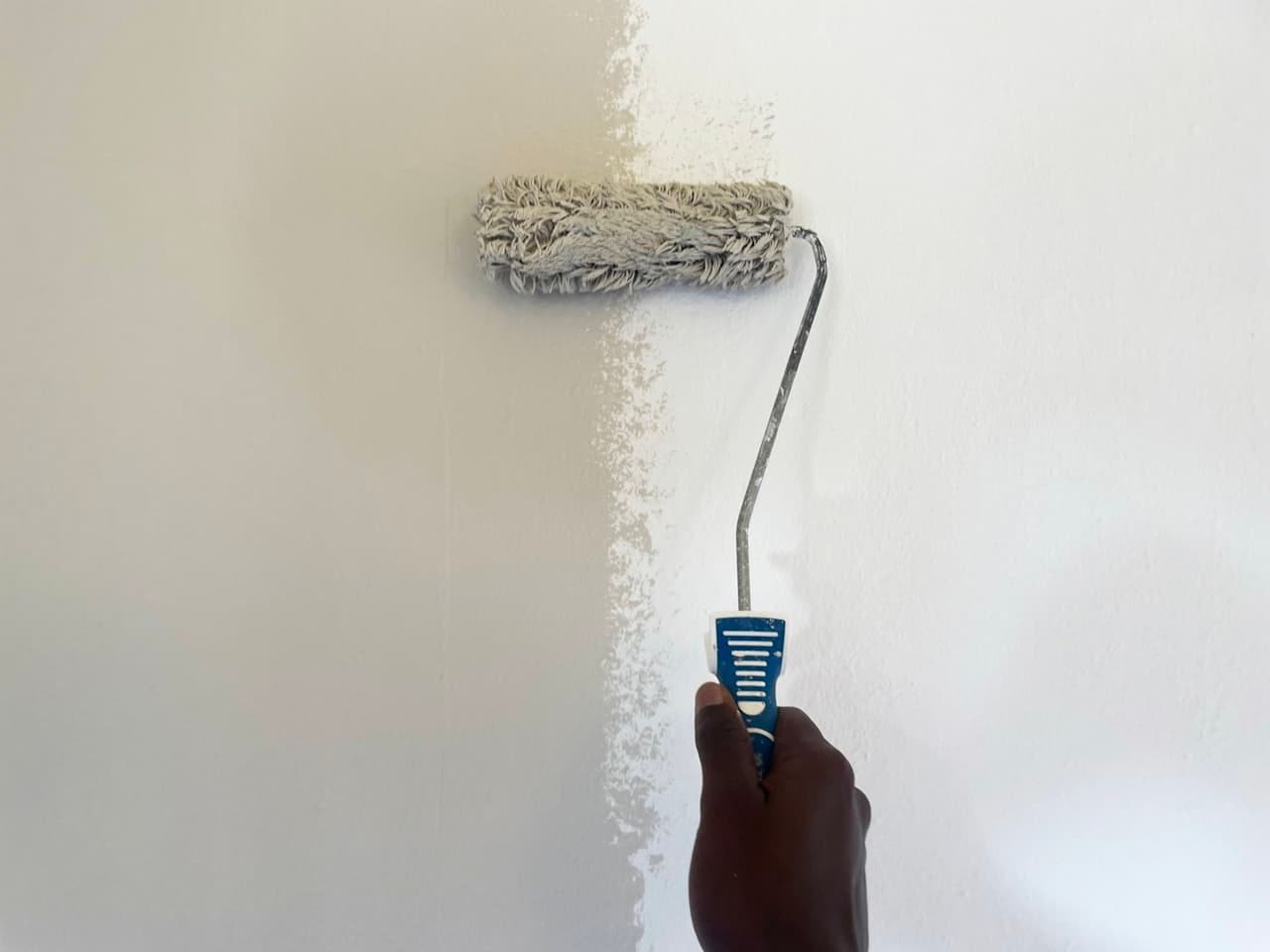 Paint roller applying fresh paint to an interior wall